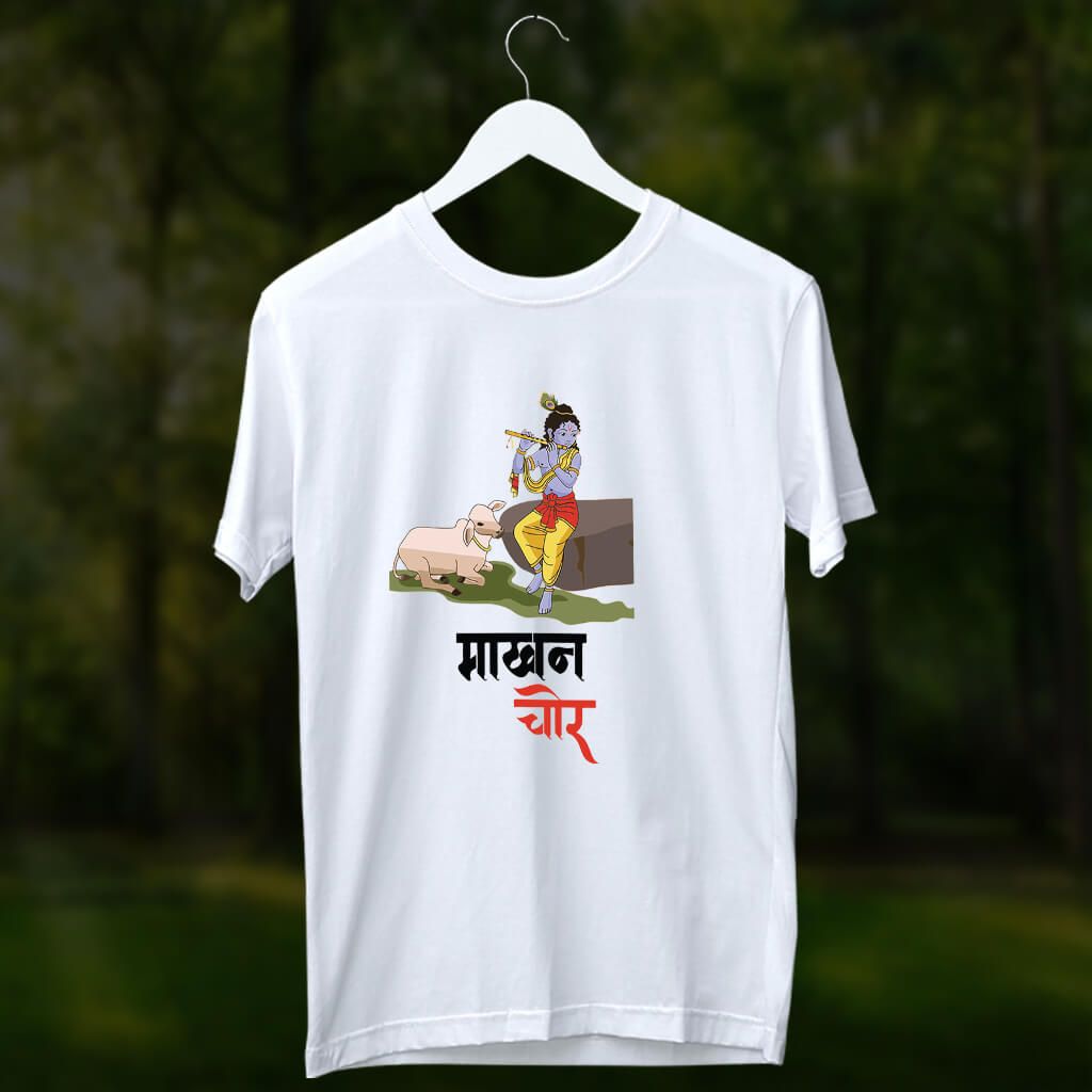 White t-shirt with a colorful illustration of Krishna playing the flute beside a cow, and "माखन चोर" (Makhan Chor) written in Devanagari script below.