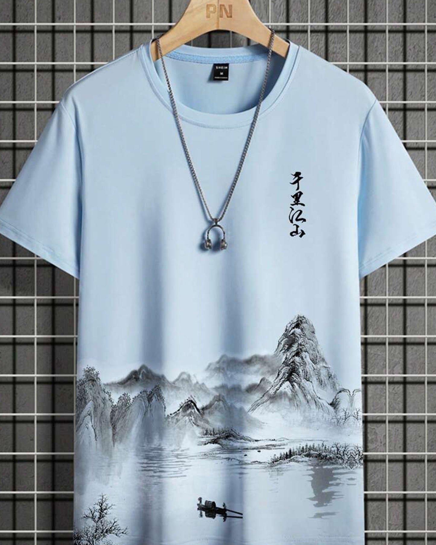 Light blue t-shirt with a landscape painting featuring mountains and Asian calligraphy, displayed with a silver necklace.