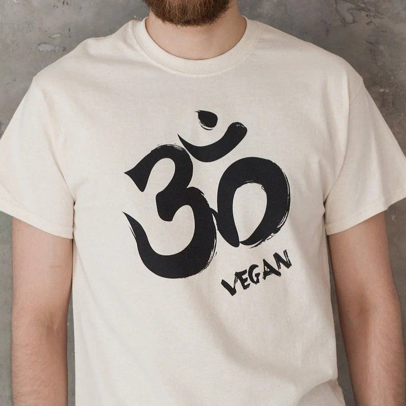 Off-white T-Shirt with a black Om symbol and the word "VEGAN" written below it.