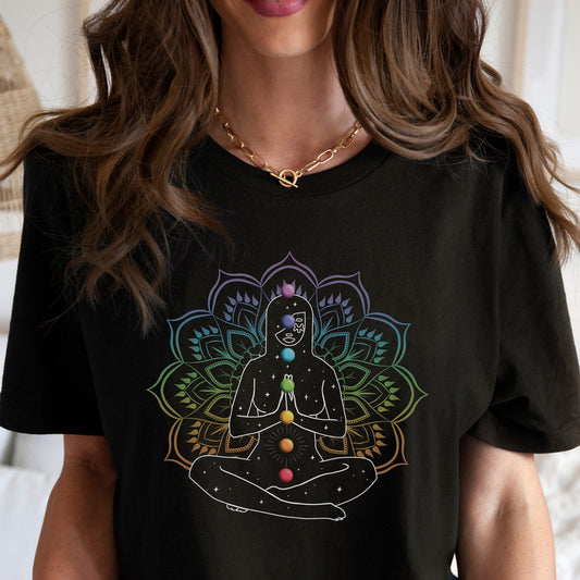 Black T-Shirt with a graphic of a woman meditating in a lotus position, displaying the seven chakra colors along her body, set against a colorful mandala design.