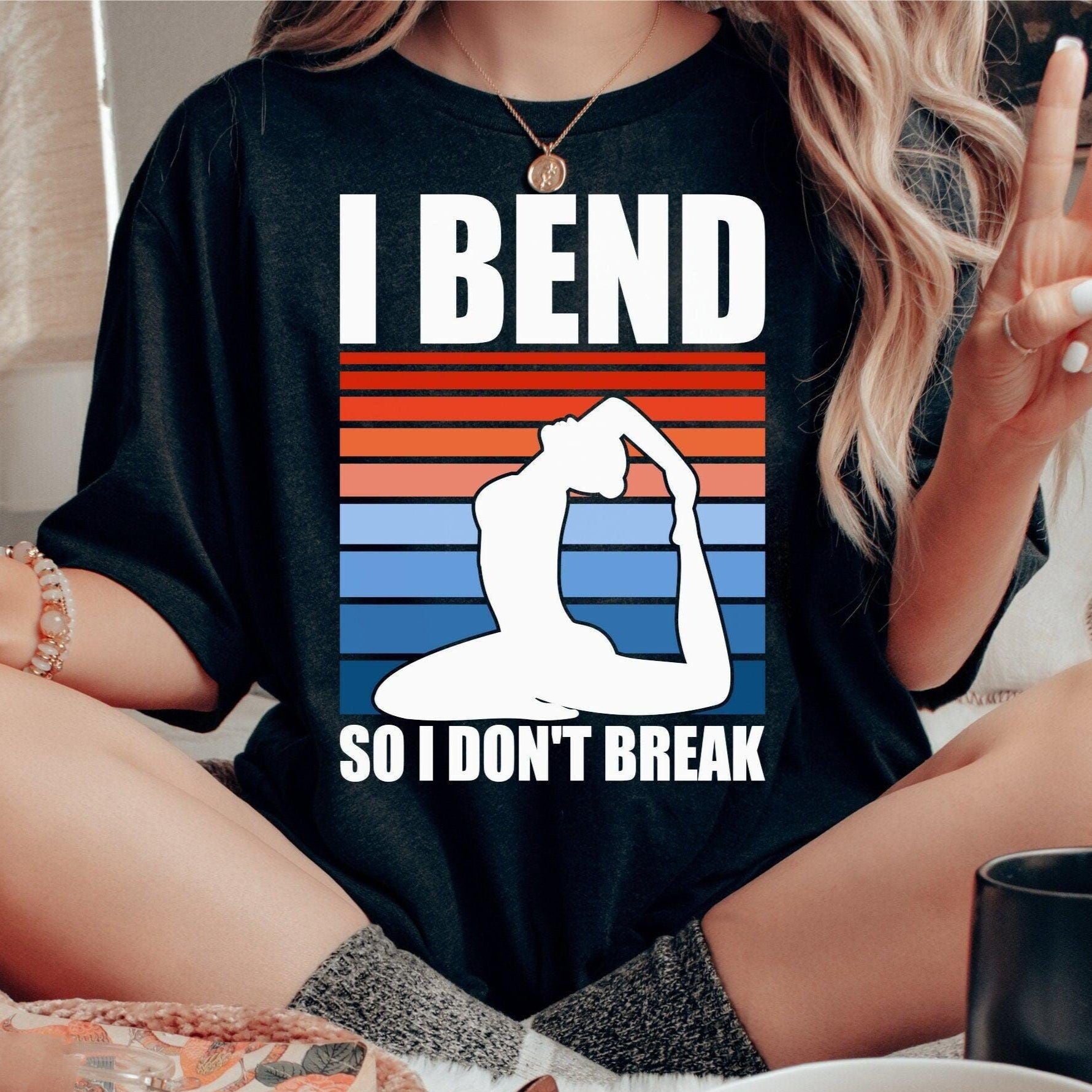 Black t-shirt with "I Bend So I Don't Break" quote, yoga pose silhouette, and striped background.
