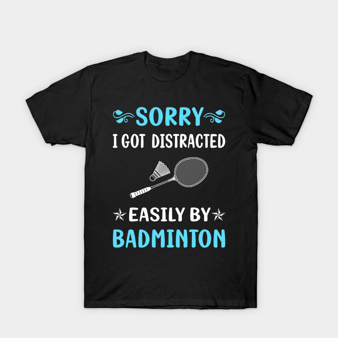 Black T-shirt with blue and white text reading 'Sorry I Got Distracted Easily by Badminton,' featuring a racket and shuttlecock graphic.