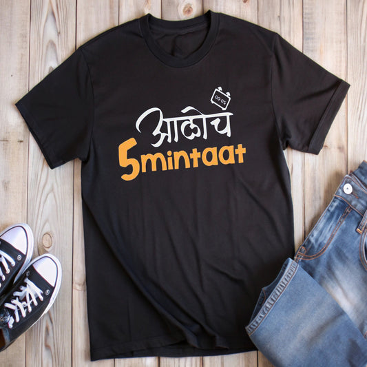 Black t-shirt with white and orange Marathi text "आलोच 5 minitaat" and a timer graphic, styled with jeans and sneakers.
