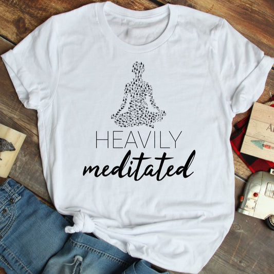 White t-shirt with "Heavily Meditated" text and a yoga pose silhouette filled with smaller yoga poses.