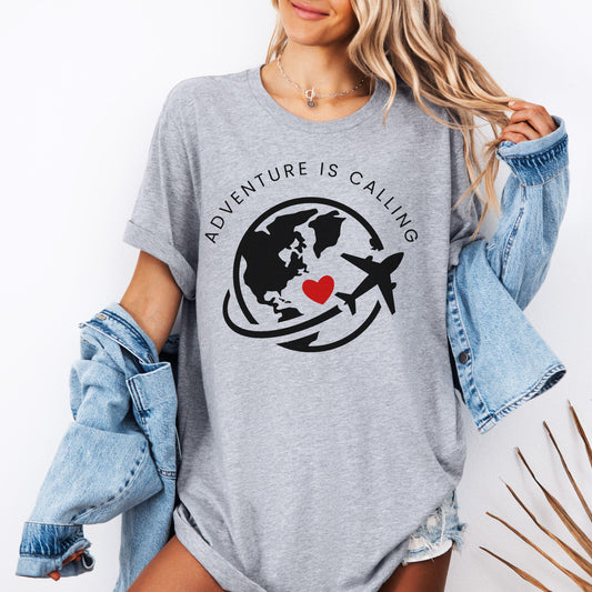 Gray t-shirt featuring a world globe, airplane, red heart, and the text "ADVENTURE IS CALLING".