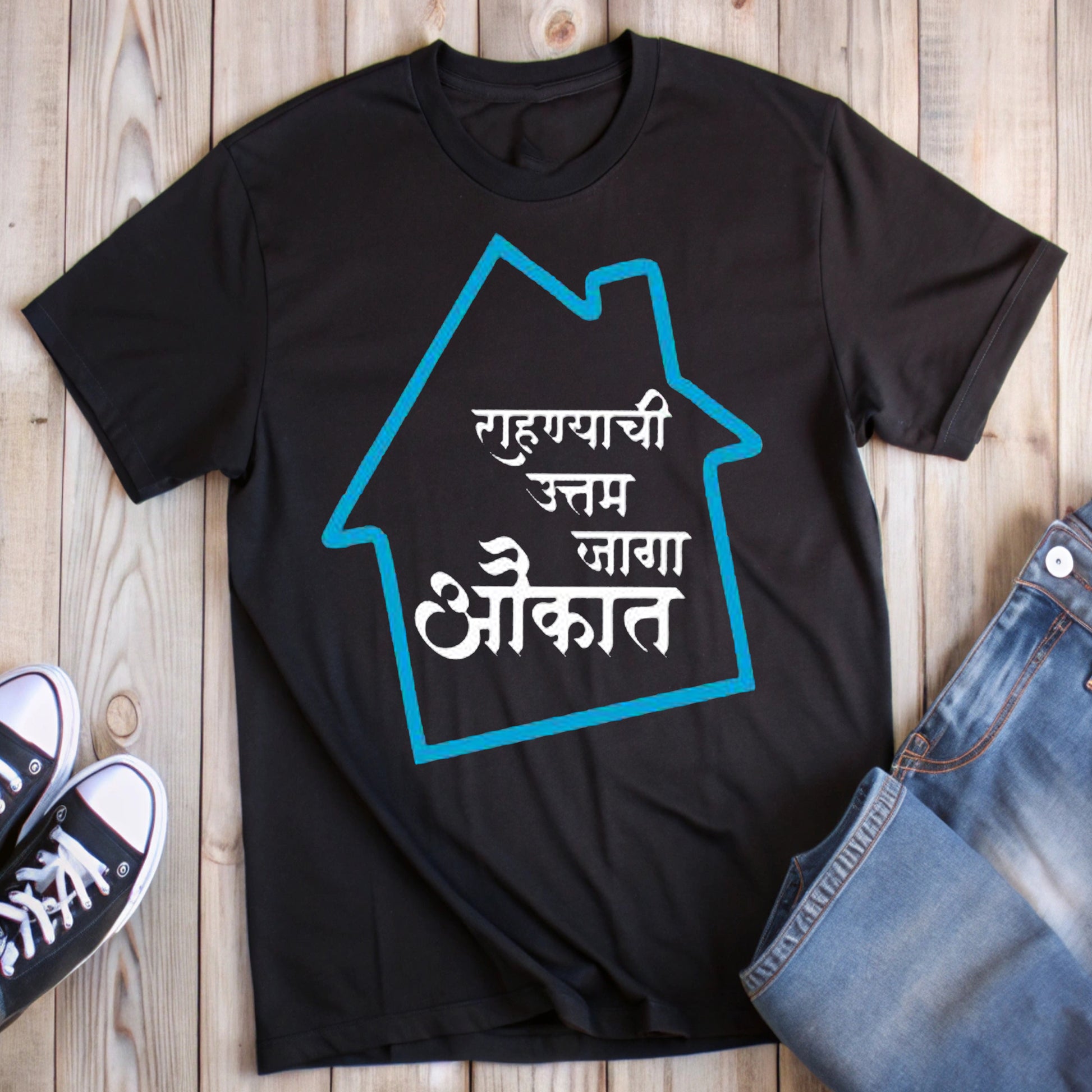  Black t-shirt with a blue house outline and white Marathi text "राहण्याची उत्तम जागा औकात" (The best place to live is within your means), styled with jeans and sneakers.