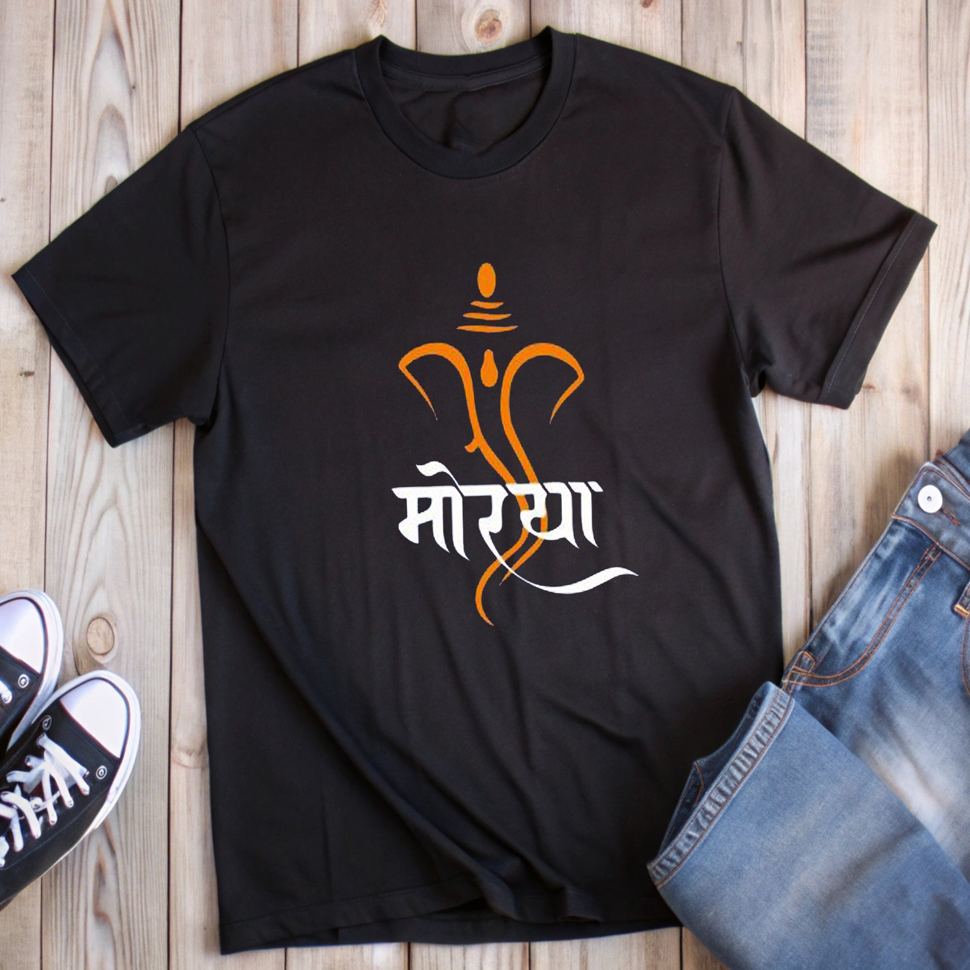  Black t-shirt featuring an orange outline of Lord Ganesha's face with the white Marathi word "मोरया" (Morya), styled with jeans and sneakers.