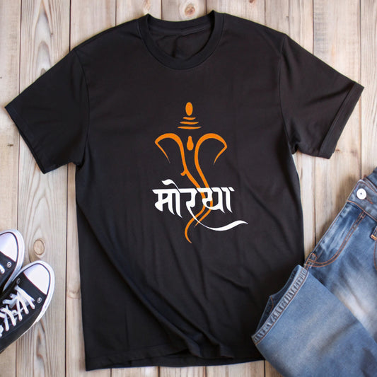  Black t-shirt featuring an orange outline of Lord Ganesha's face with the white Marathi word "मोरया" (Morya), styled with jeans and sneakers.