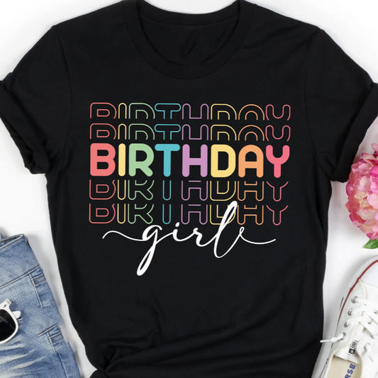 Black t-shirt with "Birthday" repeated in a retro rainbow font and "girl" in script. Casual, comfortable fit.