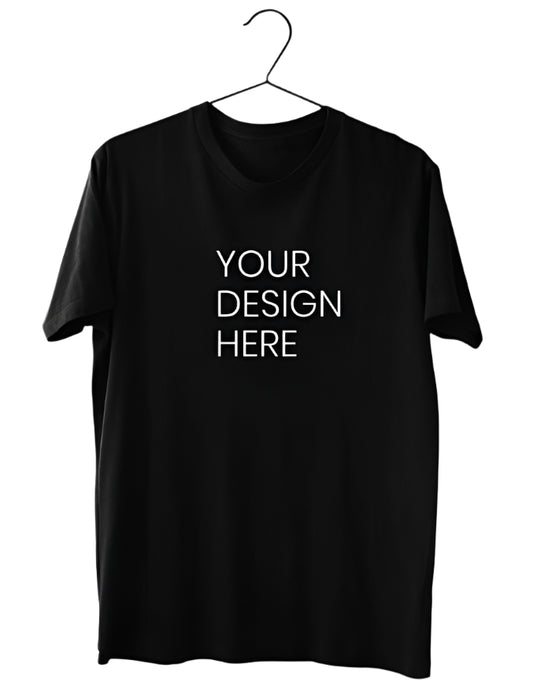A plain black cotton T-Shirt is displayed hanging on a black hanger against a light gray background, featuring a central white text area that reads "YOUR DESIGN HERE" indicating space for personalization.