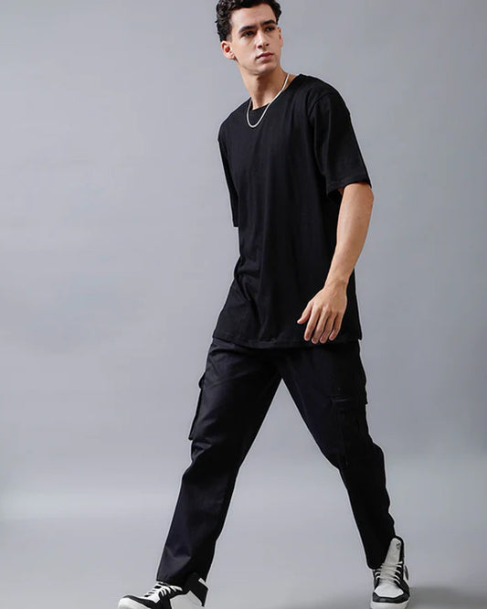 A man wearing a black t-shirt and black cargo pants  posses