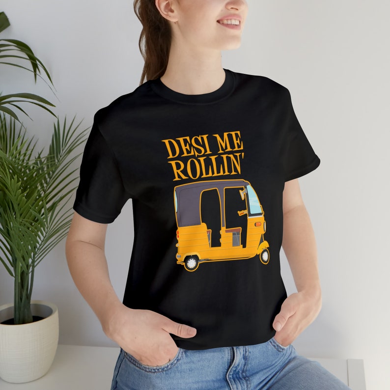 A smiling woman models a black t-shirt with a yellow auto rickshaw graphic and the text "Desi Me Rollin'".