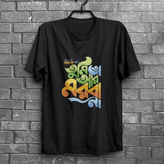 Black t-shirt with multicolored Bangla text hanging on a dark brick wall.