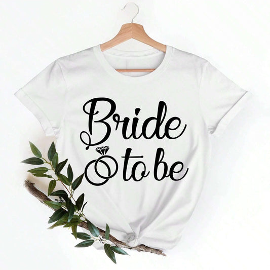 White cotton t-shirt with "Bride" in cursive above a diamond ring graphic and "to be" in smaller cursive text.