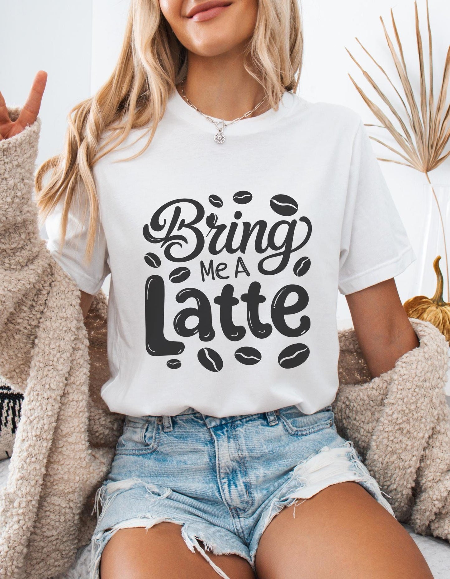 White t-shirt with "Bring Me a Latte" text and coffee bean graphics. A casual design for latte enthusiasts.