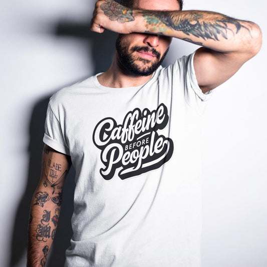 White t-shirt with "Caffeine Before People" text and a man covering his eyes with his arm. A humorous design for coffee lovers.