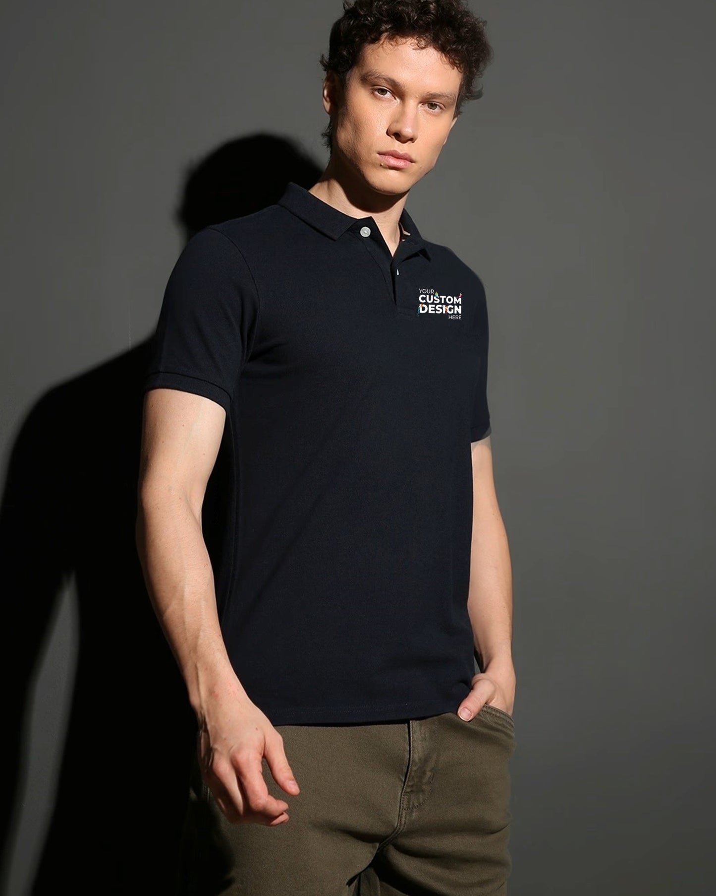 A man poses in a dark black polo t-shirt that says "Your Custom Design Here".