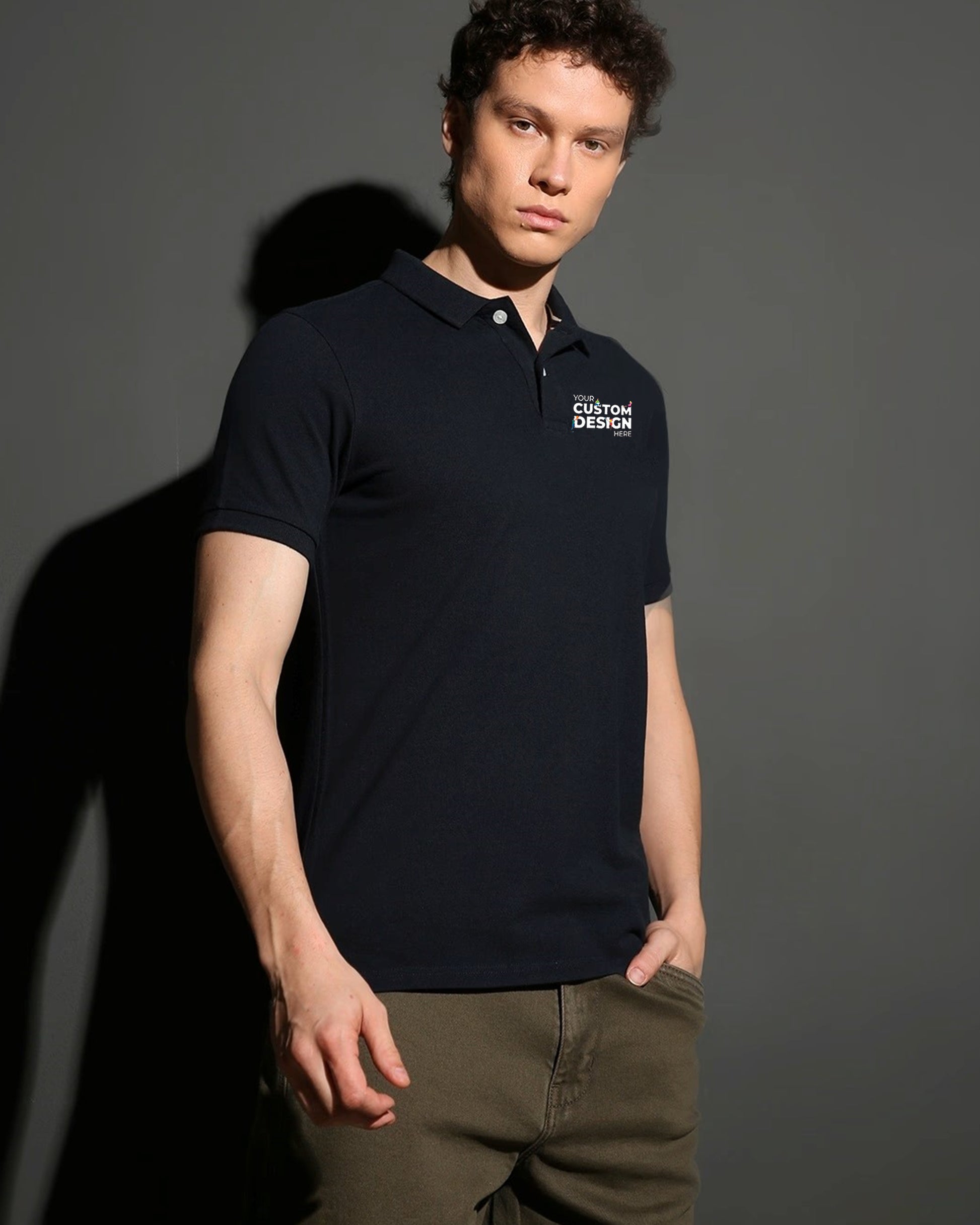 A man poses in a dark black polo t-shirt that says "Your Custom Design Here".