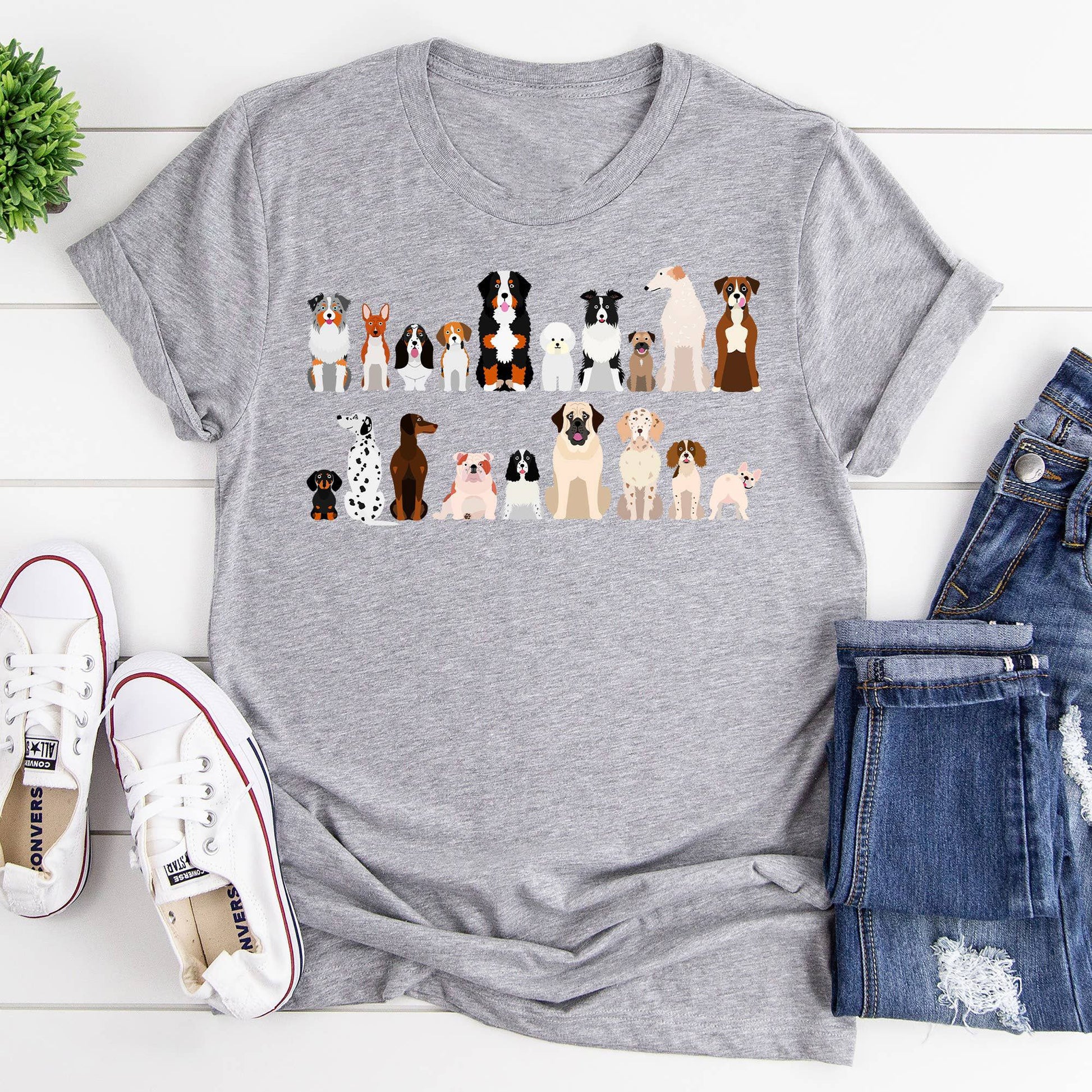 A gray t-shirt with a row of cartoon dog breeds is laid flat with shoes and jeans.
