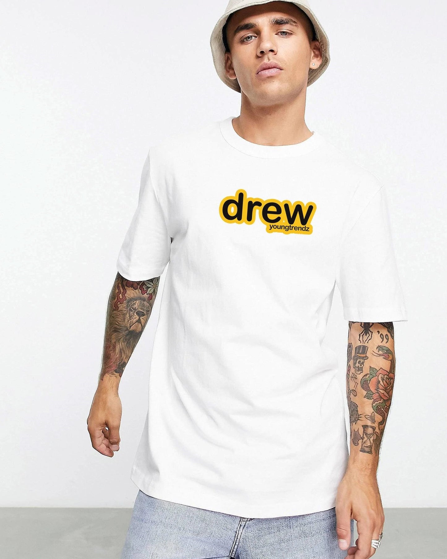 A person with tattoos wears a white t-shirt with a yellow "drew young trendz" logo and a bucket hat.