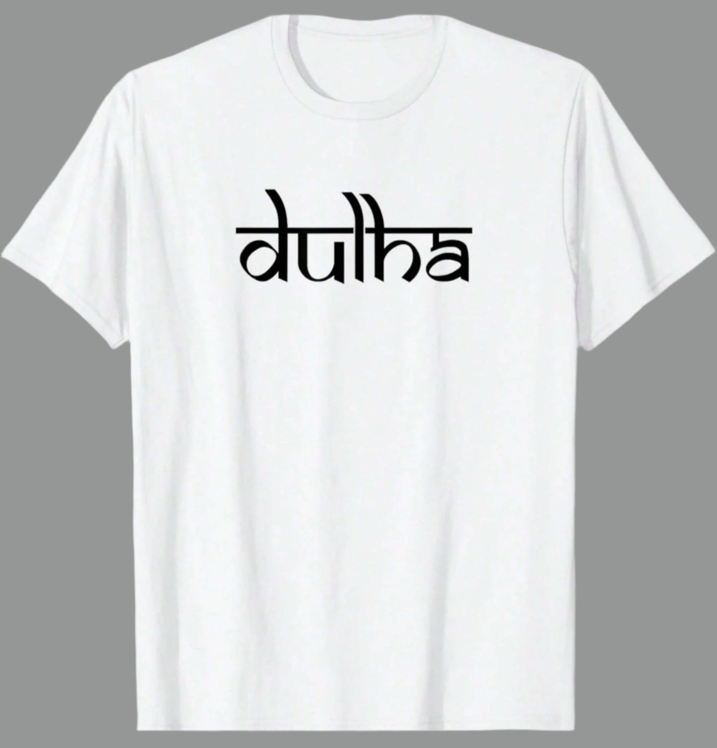 White cotton t-shirt with the word "dulha" printed in a stylized black script font. Based on the text, this likely relates to a groom in an Indian wedding context.