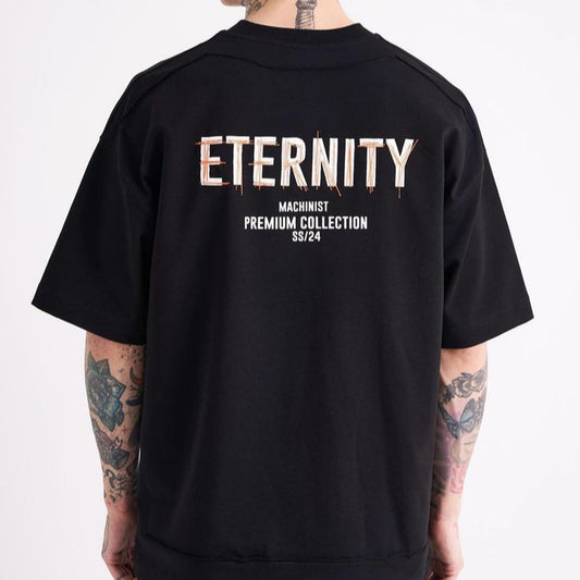 Dark-colored oversize t-shirt with "Eternity", "Machinist Premium Collection", and "SS/24" text printed on the back.