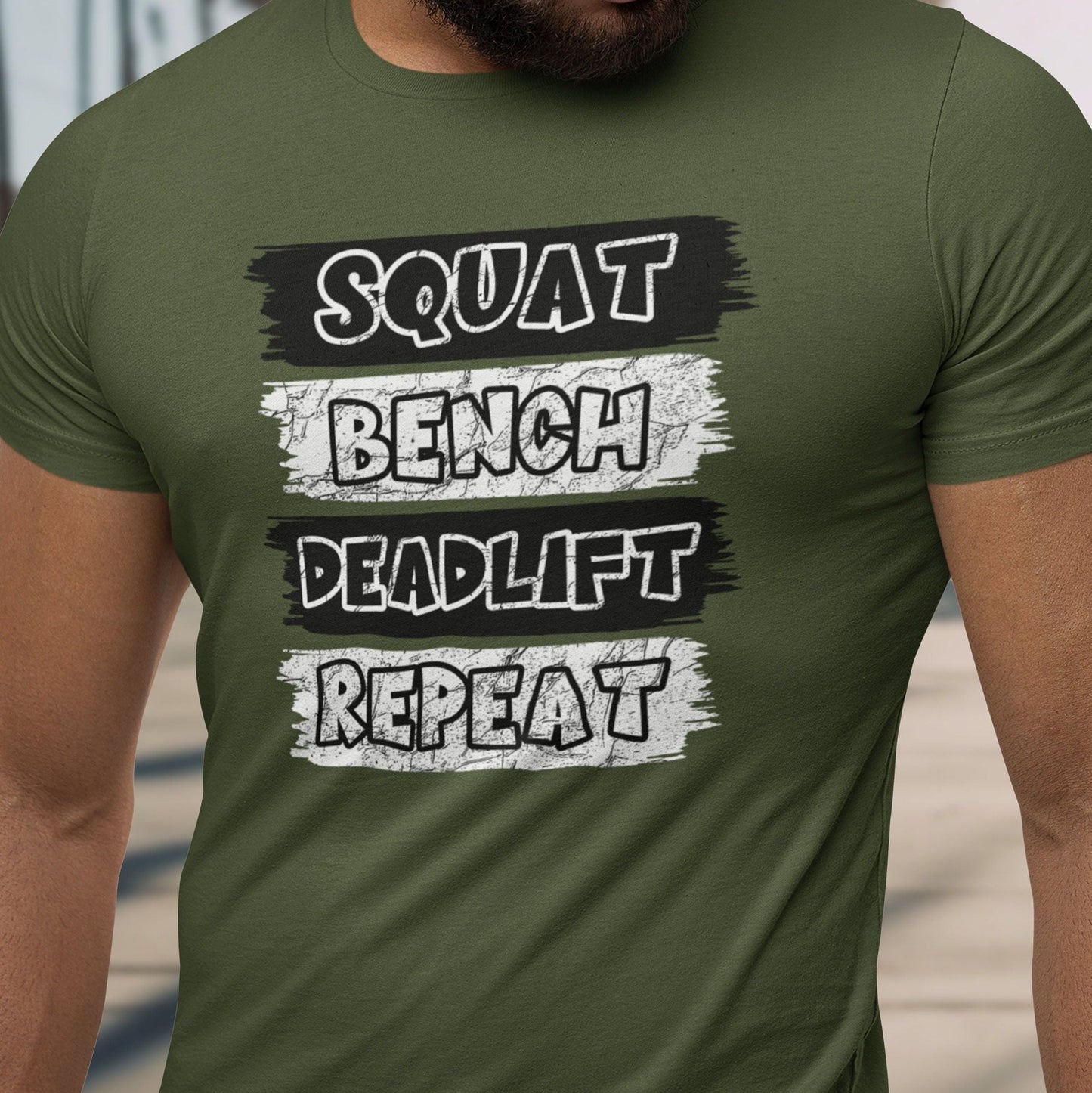 Green t-shirt with "SQUAT BENCH DEADLIFT REPEAT" text on muscular man.