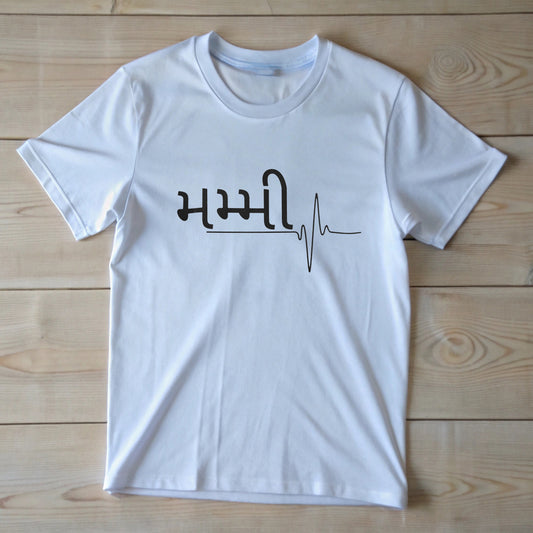 White t-shirt with "મમ્મી" (Mommy) written in black Gujarati script, followed by a heartbeat line design. Cotton blend t-shirts, available in various sizes.