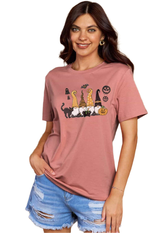 Woman wearing a pink t-shirt with Halloween gnomes, ghosts, and pumpkin graphics.