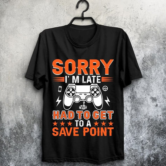  Black t-shirt with orange and white text "SORRY I'M LATE HAD TO GET TO A SAVE POINT" and a game controller graphic.