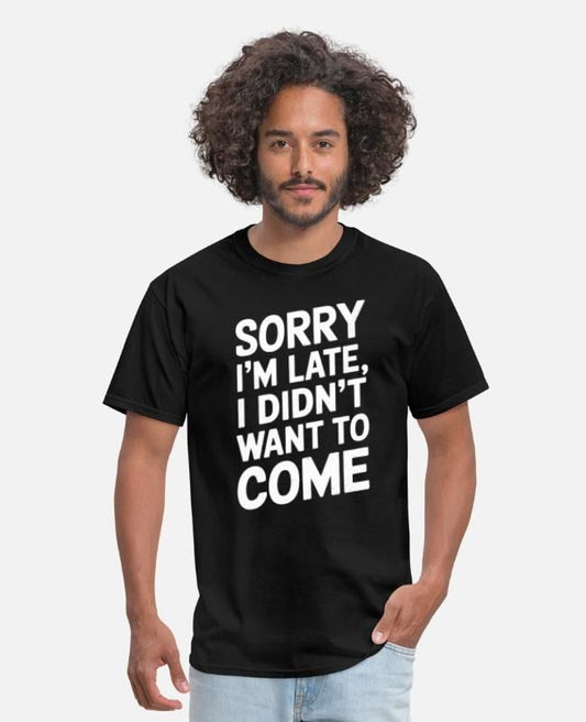 A man with curly hair wearing a black t-shirt with white text "SORRY I'M LATE, I DIDN'T WANT TO COME".