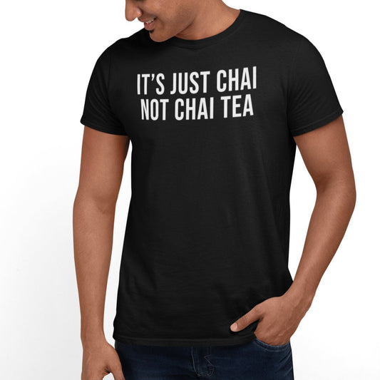Black t-shirt with "It's Just Chai Not Chai Tea" text in white. A humorous design for chai lovers with a cultural understanding of the drink. Based on the image, the man appears to be of South Asian descent.