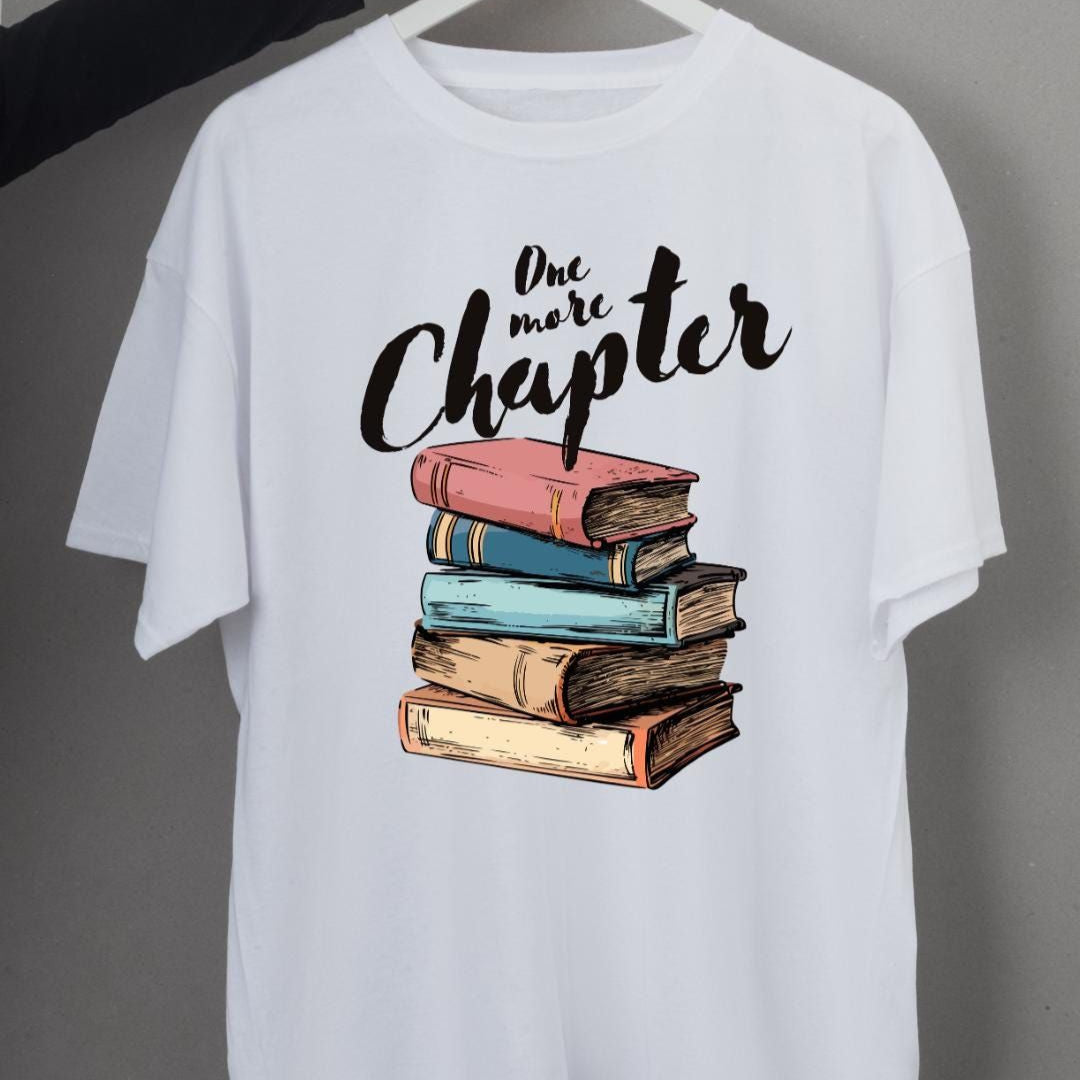 White t-shirt with a stack of colorful books and "Just One More Chapter" text.  A perfect gift for book lovers and avid readers.