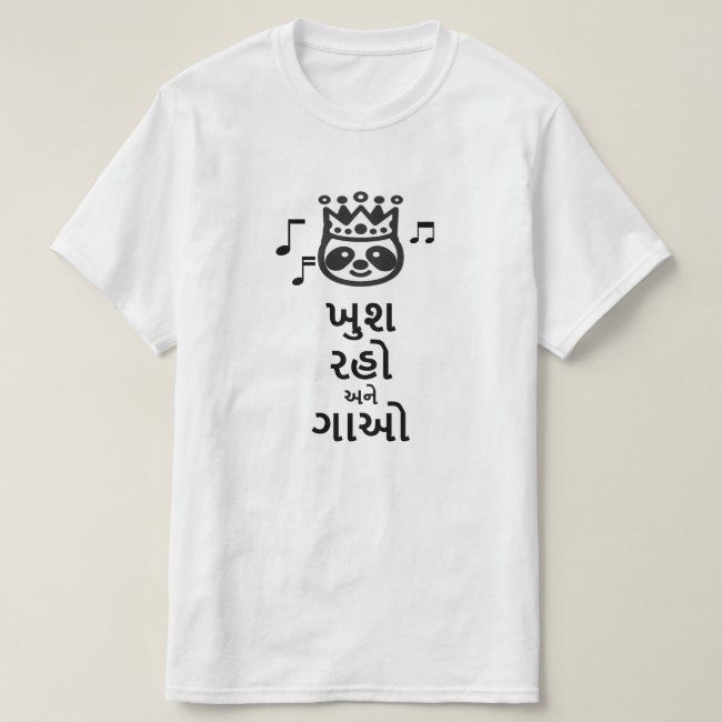 White t-shirt with a black cartoon-like face with a crown, musical notes, and the Gujarati phrase "ખુશ રહો અને ગાઓ" (khush raho ane gā'o - be happy and sing) in black text. Cotton blend t-shirts, available in various sizes.