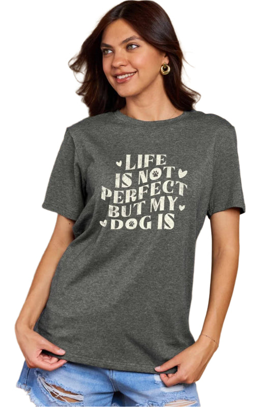 A woman in a gray t-shirt with a dog-themed quote poses against a textured wall