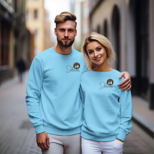 A man and woman stand close together wearing matching light blue sweatshirts with a small logo on the chest.