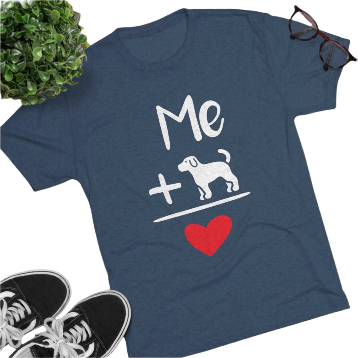 Blue t-shirt with white text "Me + Dog" and a red heart, flat lay on wooden floor with shoes and glasses.