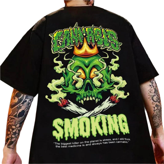 Dark-colored oversized t-shirt with a back print featuring a green skull with a crown, the word "Cannabis" in a dripping font, and the word "Smoking" below.