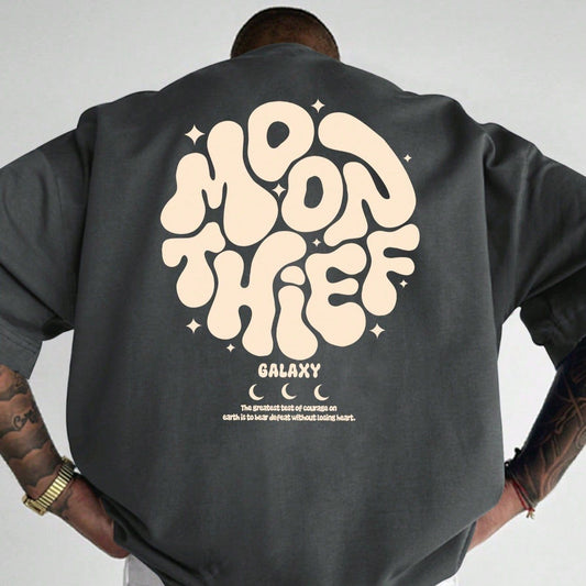 Dark-colored oversized t-shirt with a "Moon Thief" graphic in a rounded font, "Galaxy" text, star accents, and a short quote on the back.