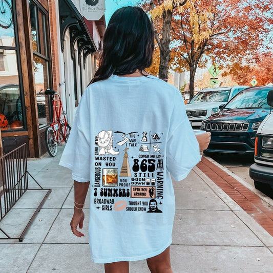 Light-colored oversized t-shirt with a collage of Morgan Wallen song titles and related graphics printed on the back.
