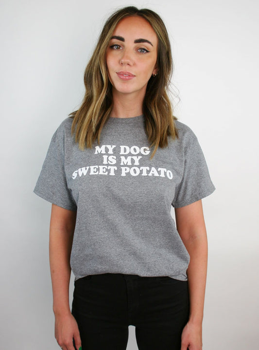  Woman wearing a gray t-shirt with white text "MY DOG IS MY SWEET POTATO" standing against a white background.