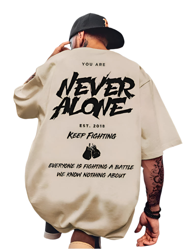 Light-colored oversize t-shirt with "You Are Never Alone", "Keep Fighting", boxing glove graphics, and "Everyone is Fighting a Battle We Know Nothing About" text on the back.