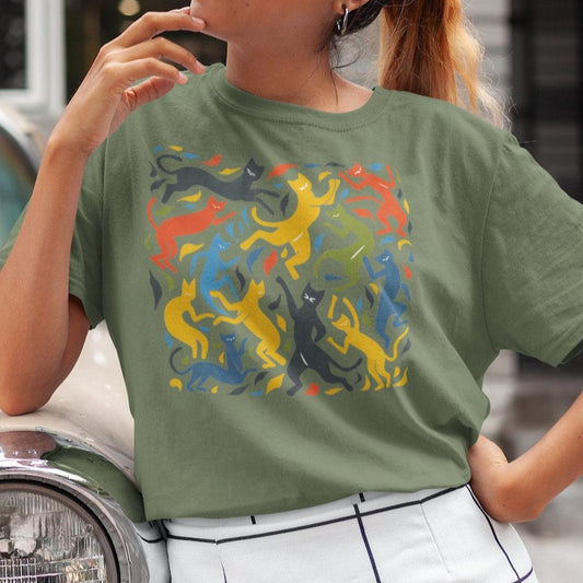 Olive green t-shirt features a colorful pattern of dancing cats reminiscent of Matisse's "The Dance."
