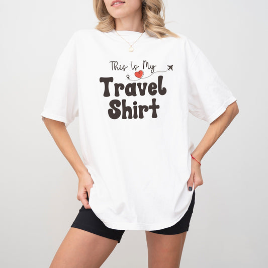 Woman wearing an oversized white t-shirt with "This Is My Travel Shirt" text.