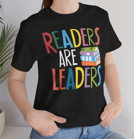 Black t-shirt with "Readers Are Leaders" in bright, multi-colored letters and a stack of books graphic. A vibrant and inspiring design for book enthusiasts.