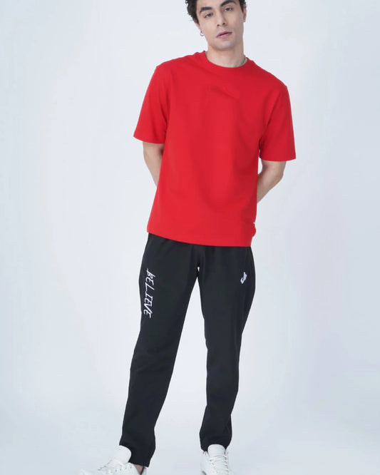 A man with dark hair wears a plain red t-shirt, shown from the side against a white background.