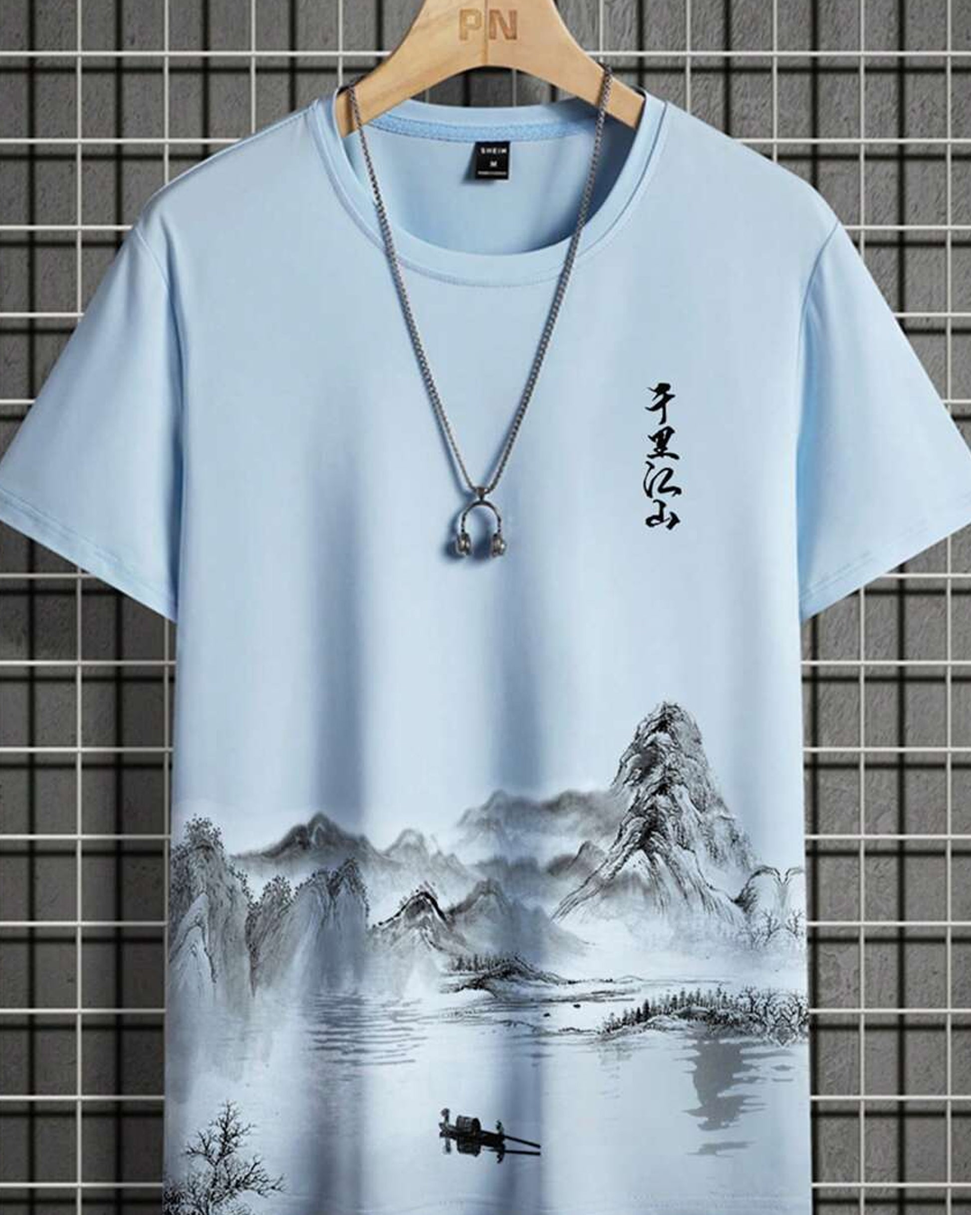 Light blue t-shirt with a landscape painting featuring mountains and Asian calligraphy, displayed with a silver necklace.