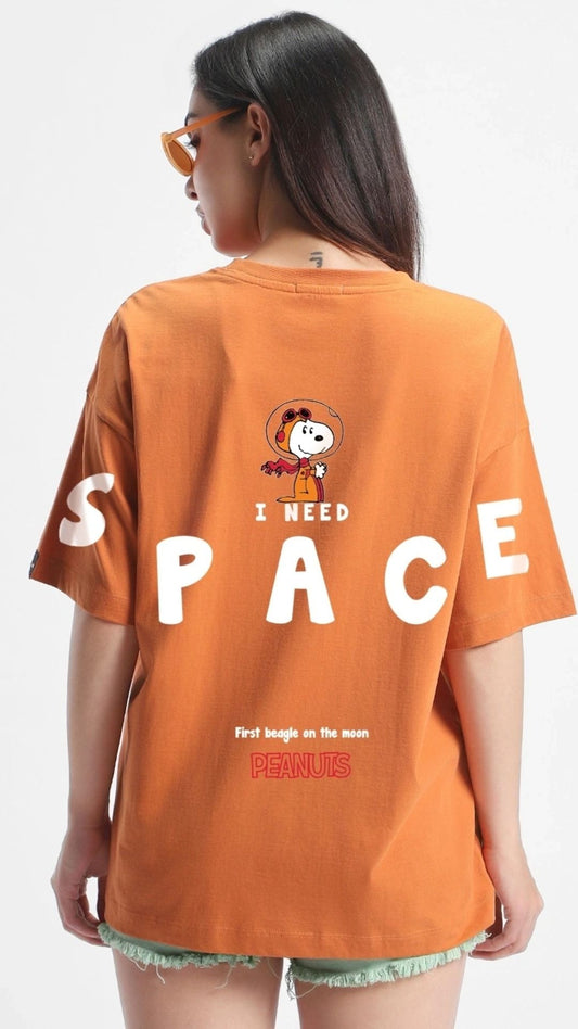 Orange oversize t-shirt with a Snoopy in space graphic, "I NEED SPACE" text, and "PEANUTS First beagle on the moon" text on the back.