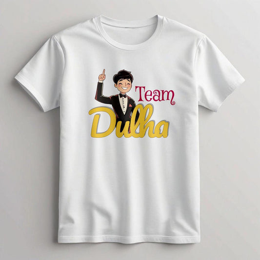 White cotton t-shirt featuring a cartoon groom in a black suit pointing upwards, with "Team" in red script and "Dulha" in large gold and red script.