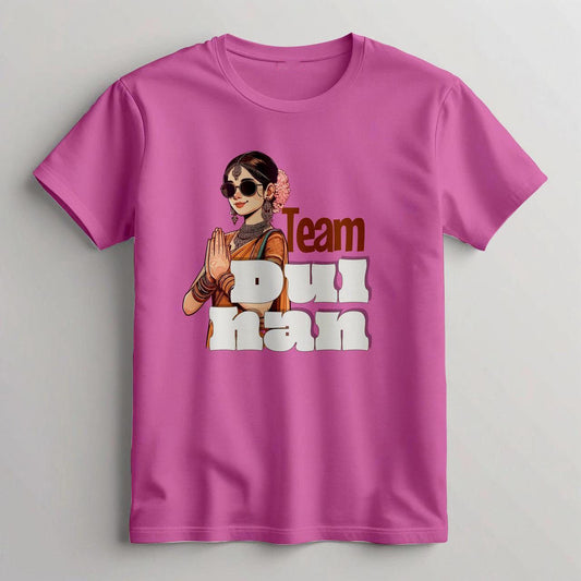 Pink t-shirt featuring a cartoon woman with sunglasses and traditional jewelry in a namaste pose, with "Team Dulhan" text, likely indicating a South Asian bride's team.